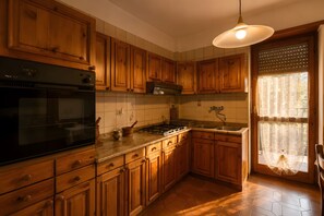 Una cocina con armarios de madera, estufa y ventana con cortinas.