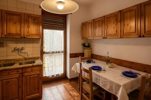 A kitchen with wooden cabinets, a sink, and a dining table set for two.