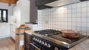 A kitchen with a gas stove, oven, and a copper pot on the stove. - Holiday Home 'Pollicina' with Mountain View and Balcony (Margno)