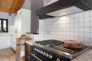 Une cuisine équipée d’une cuisinière à gaz, d’un four et d’une casserole en cuivre posée sur la cuisinière.