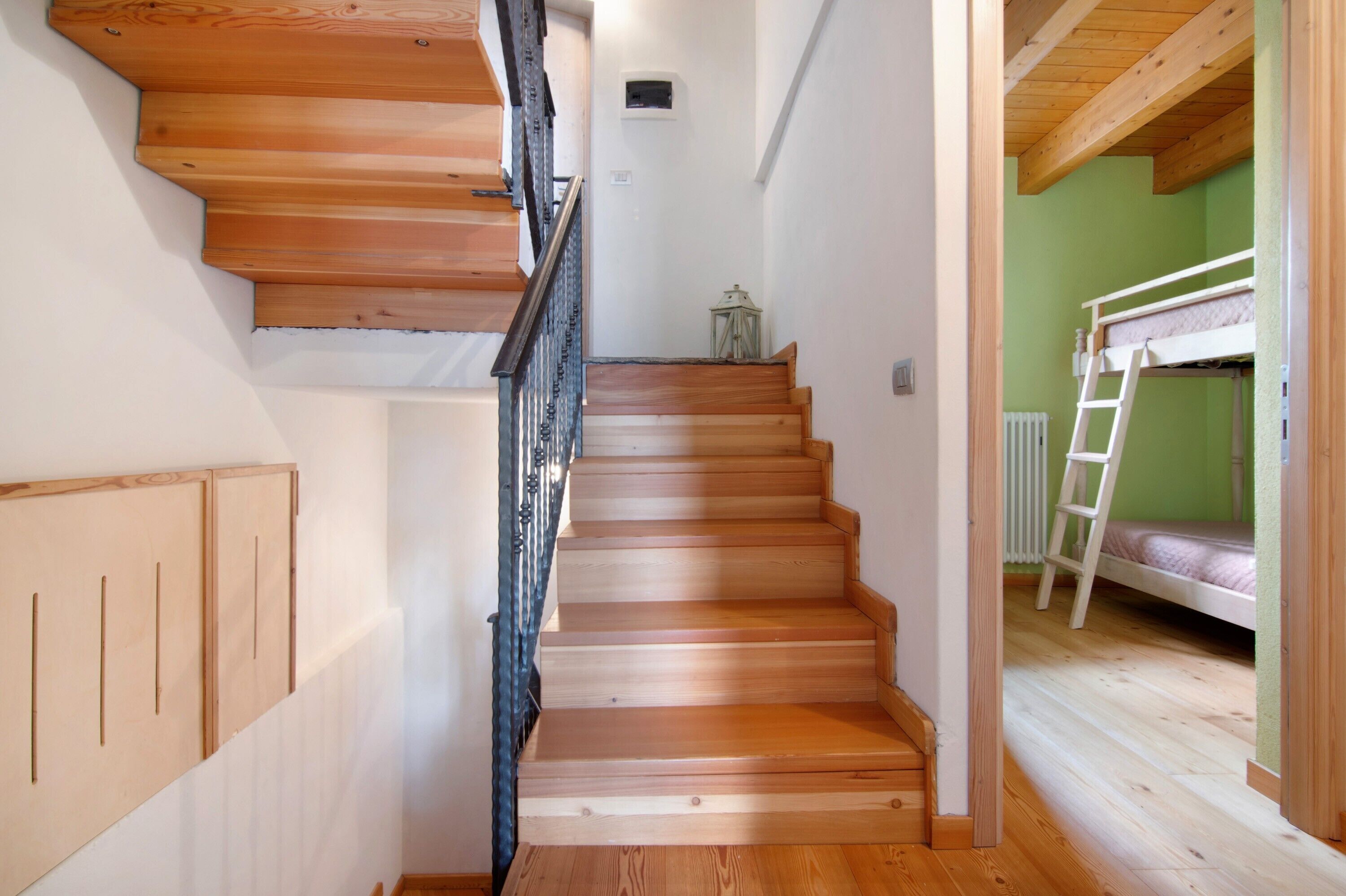 Un escalier en bois mène à une chambre avec un lit superposé, accessible par une échelle.