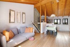 Una sala acogedora con un sofá, una mesa de comedor y una cocina al fondo.