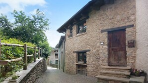 A stone building with a wooden door, steps leading to the entrance, and a stone wall on one side. - Holiday Home 'Pollicina' with Mountain View and Balcony (Margno)