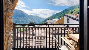 A balcony with a tiled roof, a stone wall, and a view of a mountainous landscape. - Holiday Home 'Pollicina' with Mountain View and Balcony (Margno)