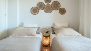 A bedroom with two beds, a bedside table with a lamp, and a wall decoration. - Apartment 'Señorio De Aloha In Puerto Banus' with Mountain View, Wi-Fi and Air Conditioning (Nueva Andalucia Marbella)