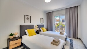 A hotel room with two beds, a nightstand, a window with curtains, and a view of the outside. - Apartment 'Señorio De Gonzaga In Marbella' with Shared Pool, Wi-Fi and Air Conditioning (Marbella)