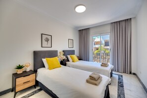 Une chambre d’hôtel avec deux lits, une table de chevet, une fenêtre avec des rideaux et une vue sur l’extérieur.