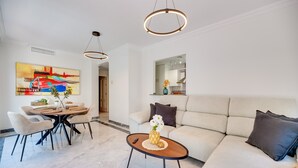 A modern living room with a dining area, a sofa, a coffee table, and a painting on the wall. - Apartment 'Señorio De Gonzaga In Marbella' with Shared Pool, Wi-Fi and Air Conditioning (Marbella)