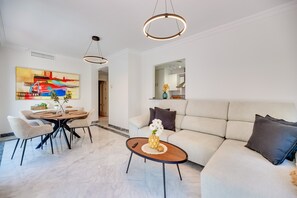 Un salon moderne comprenant un coin repas, un canapé, une table basse et un tableau accroché au mur.