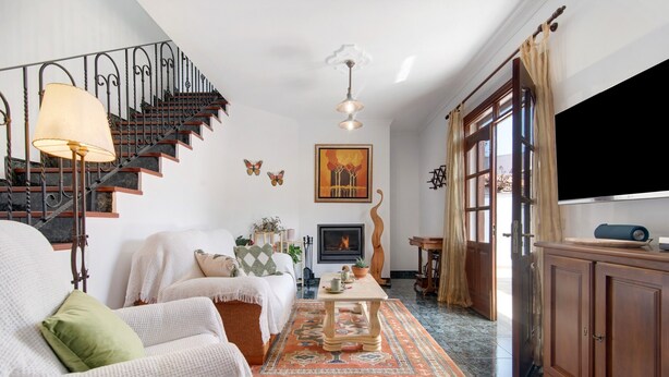A living room with a staircase, a fireplace, a television, and a large window. - Vacation Home "Las Monarcas" with Mountain View, Private Terrace & Wi-Fi (Teror)