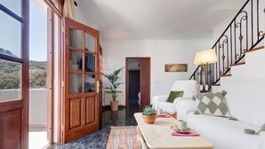 A living room with a sofa, a coffee table, a potted plant, and a staircase. - Vacation Home "Las Monarcas" with Mountain View, Private Terrace & Wi-Fi (Teror)