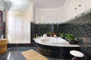 Ein Badezimmer mit einer freistehenden Badewanne, einer Holzbadezimmermatte und einem Korbwannenkorb.
