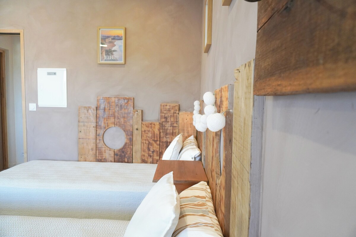 Een slaapkamer met een houten hoofdbord, een bed met witte lakens, een klein nachtkastje en een ingelijst schilderij aan de muur.