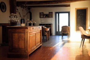 Une cuisine rustique avec des meubles en bois, un sol carrelé et un coin repas comprenant des chaises et une table.