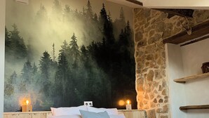 Ein Schlafzimmer mit einem Bett, einer Steinwand und einer Waldmalerei an der Wand.