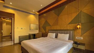 Habitación de hotel con una cama grande, una mesita de noche con lámpara y un revestimiento de madera decorativo.