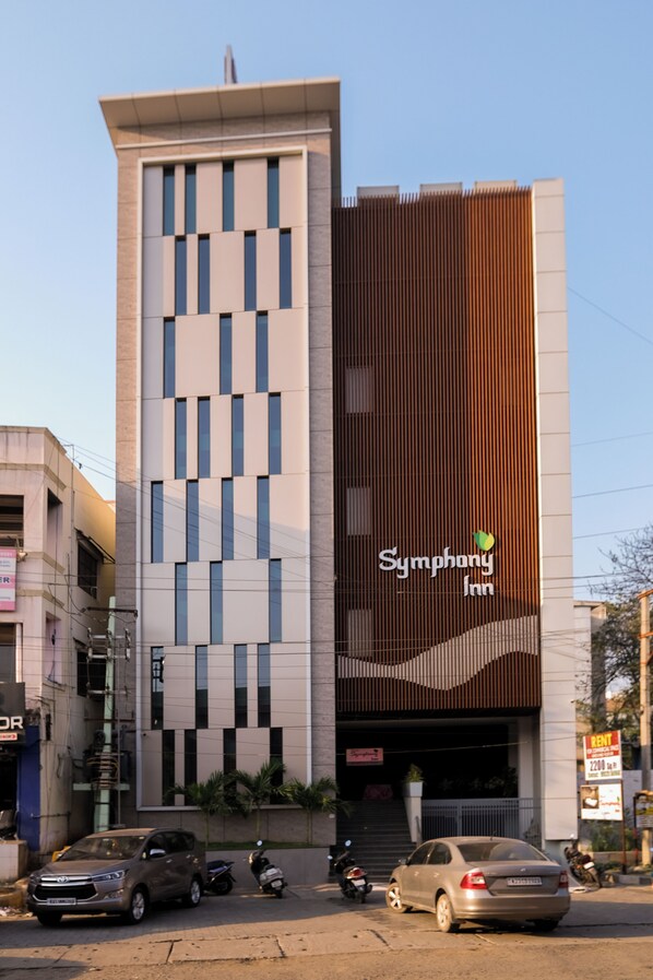 A modern building with a Symphony Inn sign, featuring a vertical wooden panel design and a series of windows.
