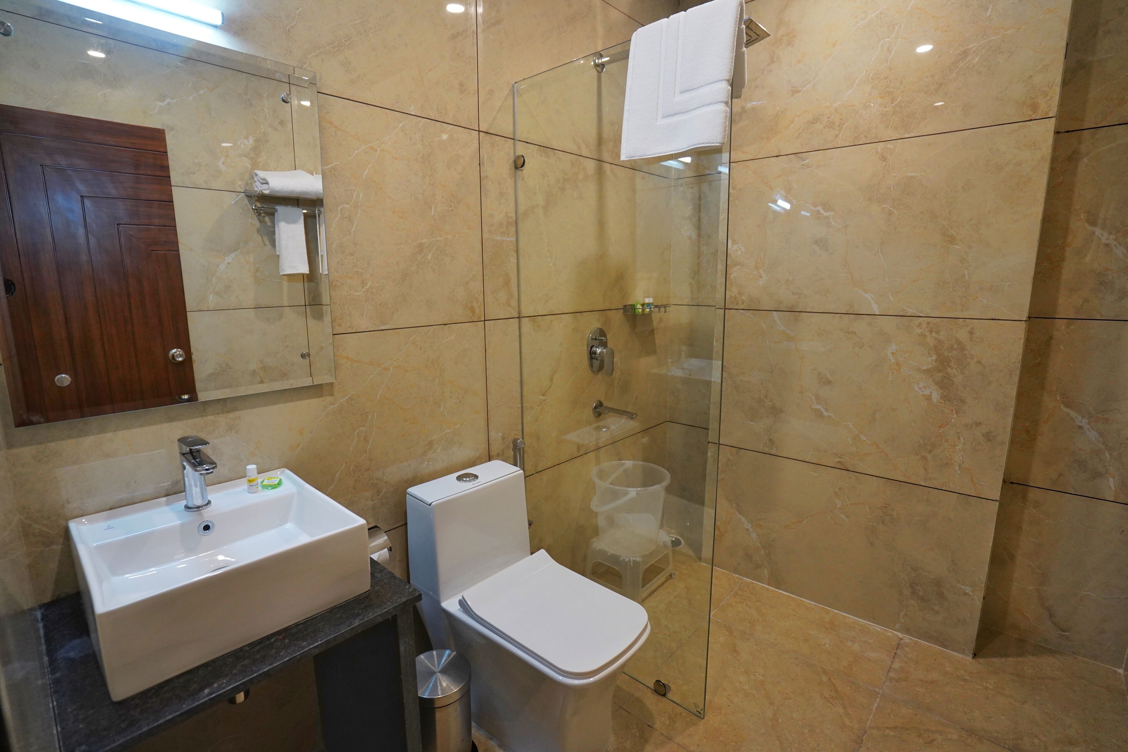 Egy modern fürőszoba üveg válaszfallal ellátott zuhanyzóval, mosdókagylóval és WC-vel.
