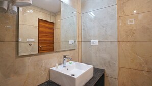 Un bany modern amb un lavabo blanc, parets de marbre i una porta de fusta.
