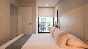 Une chambre d’hôtel avec un lit, une vue sur le balcon extérieur et une porte donnant sur une autre pièce.