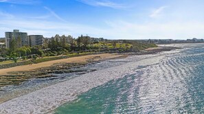 Une vue sur la côte, avec une plage de sable, une côte rocheuse et une mer bleue et limpide.