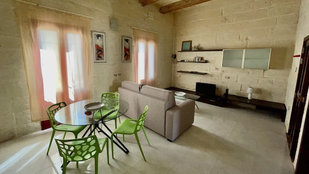 A dining area with a round table and chairs, a sofa, and a TV.
