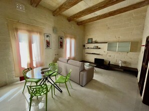A dining area with a round table and chairs, a sofa, and a TV. - Sliema heart, best spot in Malta (Tas-Sliema)