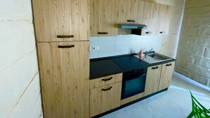 A kitchen with wooden cabinets, a black countertop, a stainless steel sink, and a built-in oven.