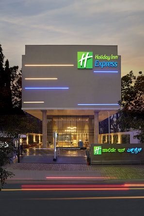 En Holiday Inn Express-byggnad med en modern design, som kännetecknas av en framträdande entré och upplyst skyltning.
