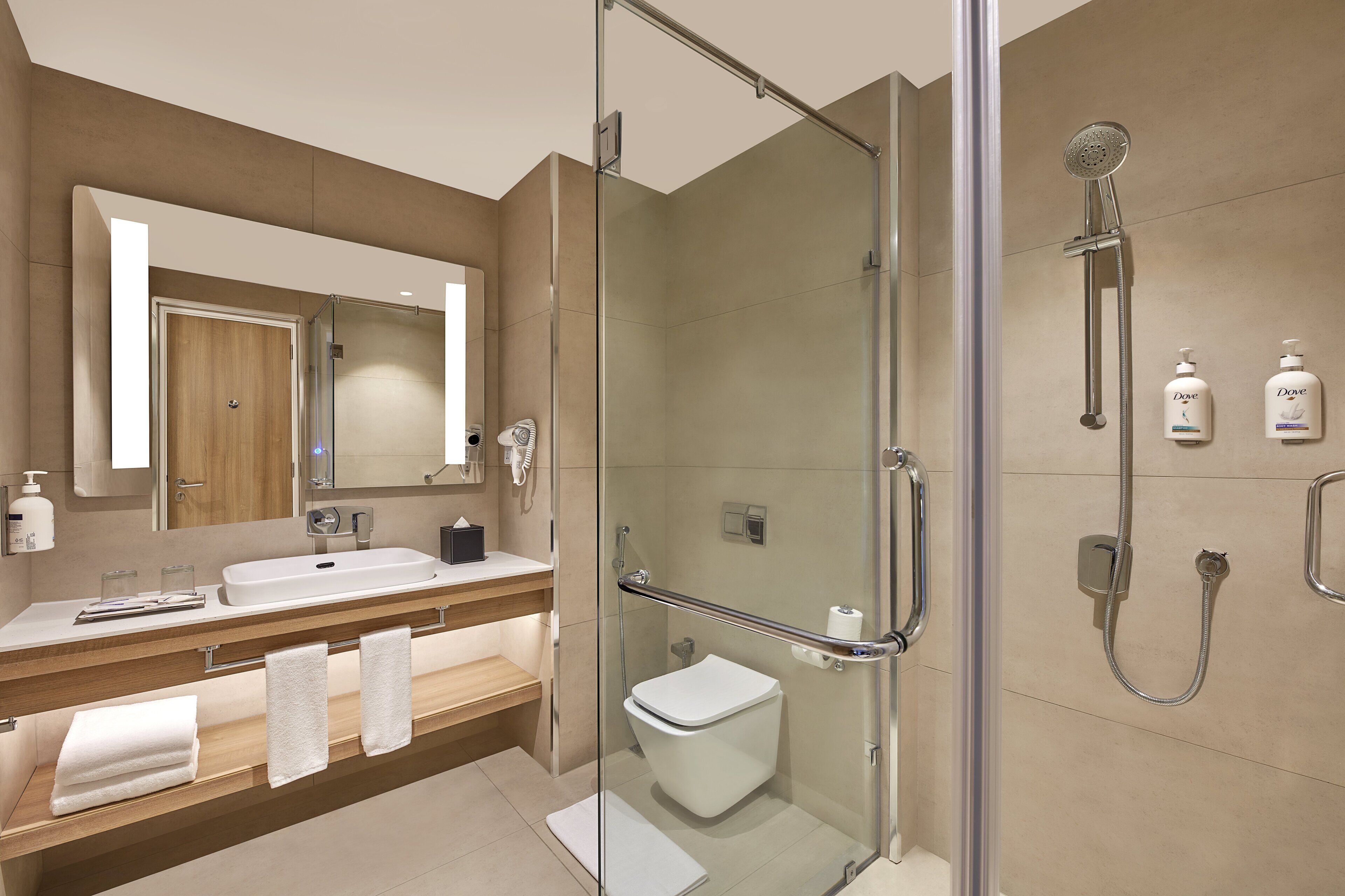 A modern bathroom with a glass-enclosed shower, a sink with a mirror, and toiletries on the wall.