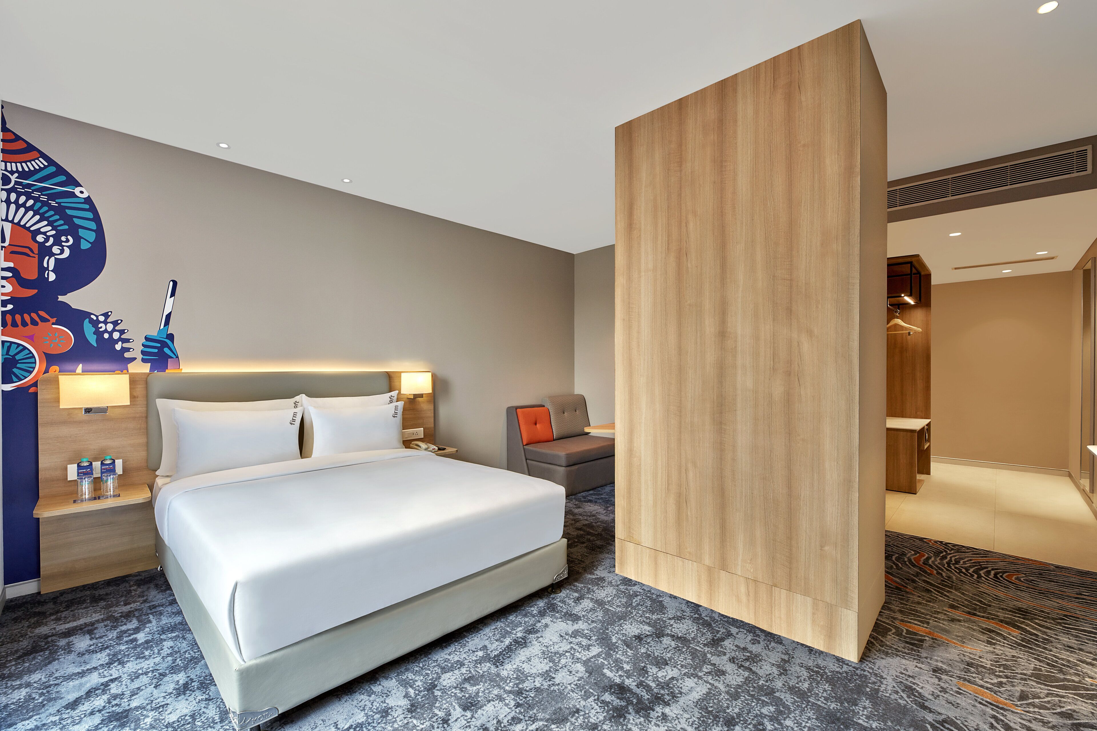 Una habitación de hotel moderna con una cama grande, una mesita de noche, un escritorio y un armario.
