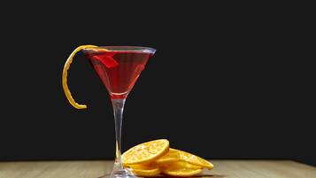 A martini glass with a lemon garnish on a wooden surface against a dark background.
