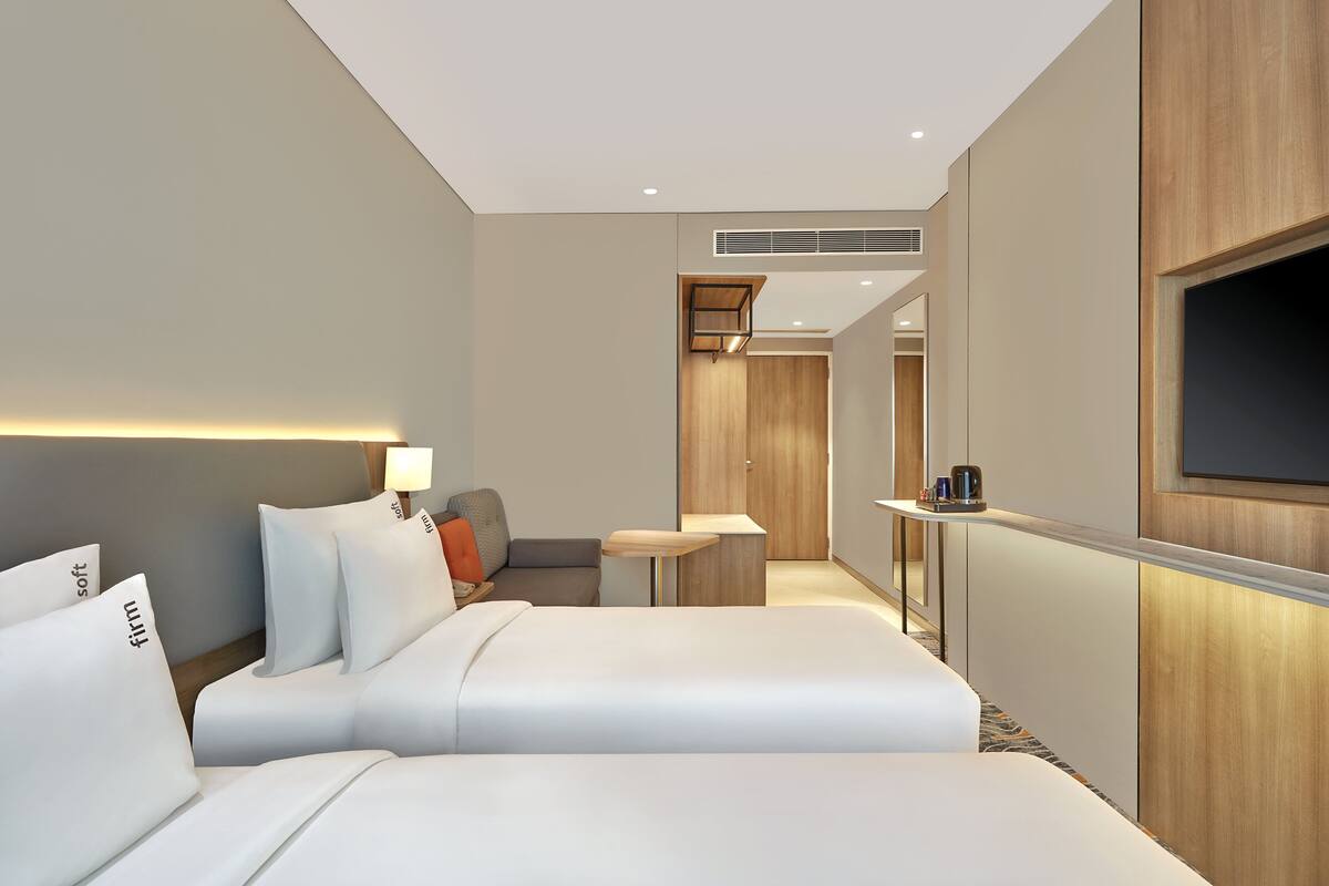 A hotel room with two beds, a sofa, a TV, and a small table.