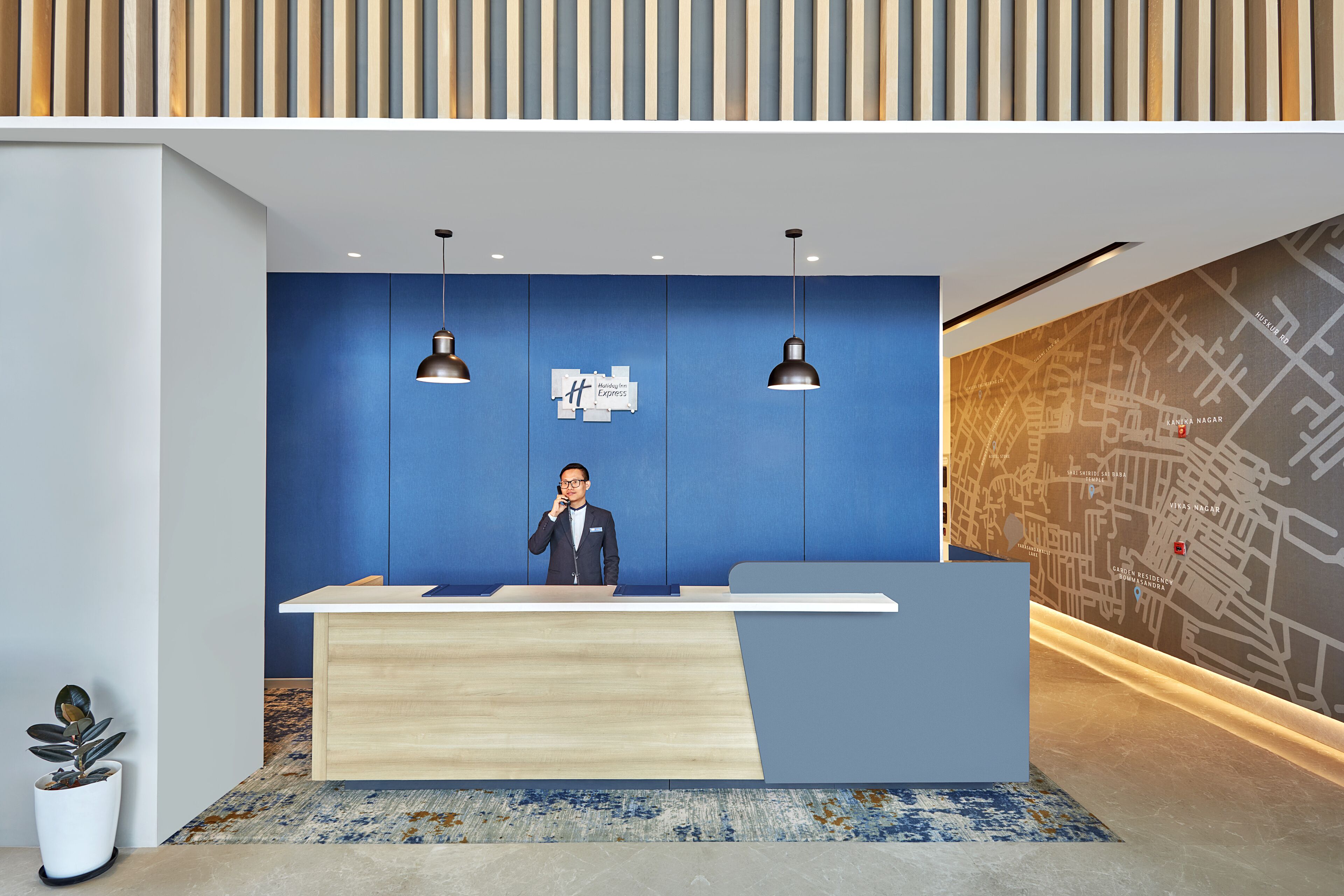 A reception desk with a blue wall, two pendant lights, and a map on the wall.
