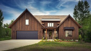 A two-story wooden house with a garage, a front porch, and a landscaped garden. - Redtail Rendezvous with Hot Tub (Driggs)