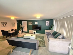 Una sala de estar con sofá, mesa de centro, televisor y un comedor con sillas y mesa.