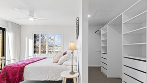 A bedroom with a bed, a bedside table with a lamp, a closet with shelves, and a window with blinds. - Architectural Home: Near Gorge with Tamar Views (Launceston)