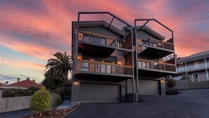 A multi-story building with a garage, balconies, and a landscaped front yard. - Architectural Home: Near Gorge with Tamar Views (Launceston)