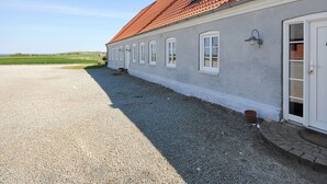 Un bâtiment à deux étages, doté d’un toit recouvert de tuiles rouges, de murs extérieurs blancs et d’une allée gravillonnée.