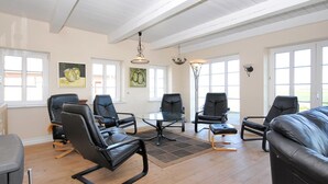 Un salon spacieux avec un plafond haut, de grandes fenêtres et un lustre moderne.