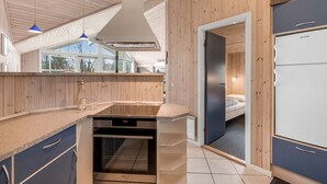 Une cuisine moderne avec un lambris en bois, un four encastré et un réfrigérateur.