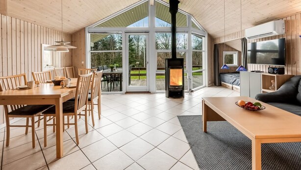 Un vaste espace de vie comprenant une grande table et des chaises en bois, un canapé, un téléviseur et une cheminée.