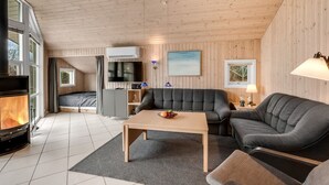 Un salon chaleureux avec une cheminée, un canapé, une table basse et un téléviseur.