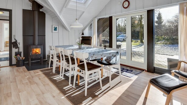 A spacious room with a large dining table, white chairs, a fireplace, and a view of the outside. - "Sighrik" - 30km from the sea by Interhome (Toftlund)