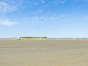Ein weiter, offener Strand mit einigen Fahrzeugen und einem kleinen Gebäude in der Ferne.