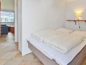 Een slaapkamer met een bed, een nachtkastje, een lamp en uitzicht op buiten.