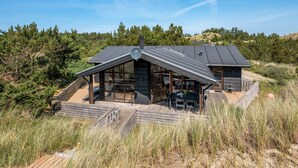 Een moderne blokhut met een schuin dak, grote ramen en een terras.