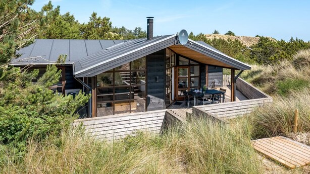 Een moderne cabin met schuin dak, grote ramen en een terras.