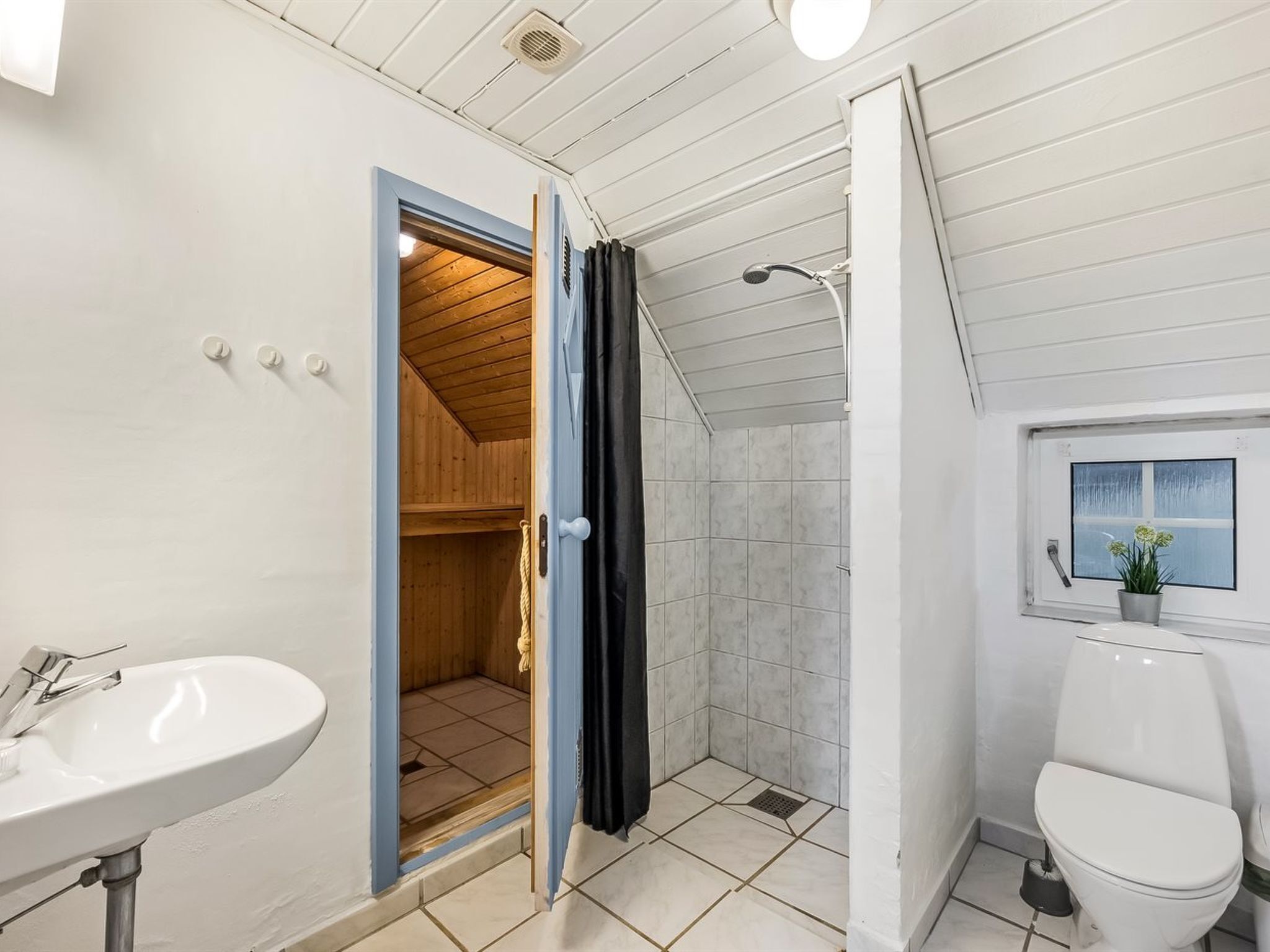 Een badkamer met een houten sauna, een witte wastafel en een toilet.