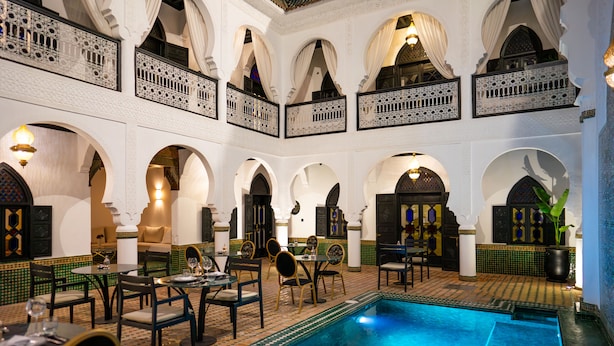 A luxurious indoor pool area with multiple arches and a dining setup. - The Grand Riad & Spa  (Marrakech)